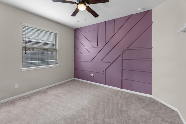 carpeted empty room with a ceiling fan and baseboards