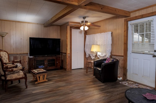 living area with beam ceiling, wooden walls, and wood finished floors