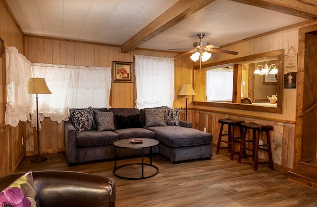 living room with beamed ceiling, wood walls, ceiling fan, and wood finished floors