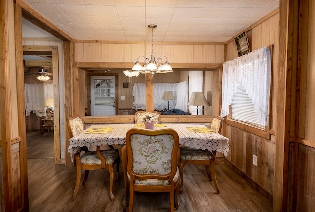 dining room featuring wooden walls, wood finished floors, and a chandelier