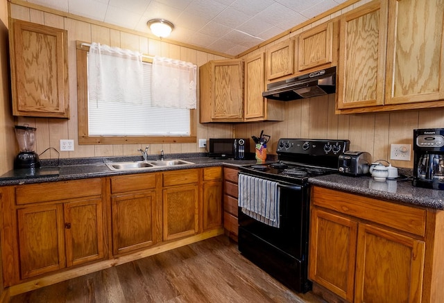 kitchen featuring under cabinet range hood, black appliances, dark countertops, and a sink