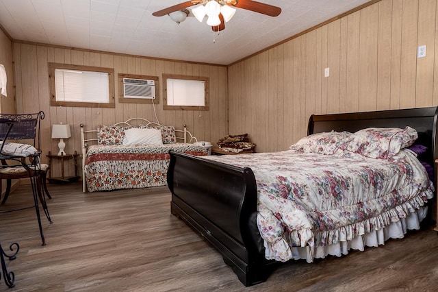 bedroom featuring ornamental molding, a wall mounted air conditioner, ceiling fan, and wood finished floors