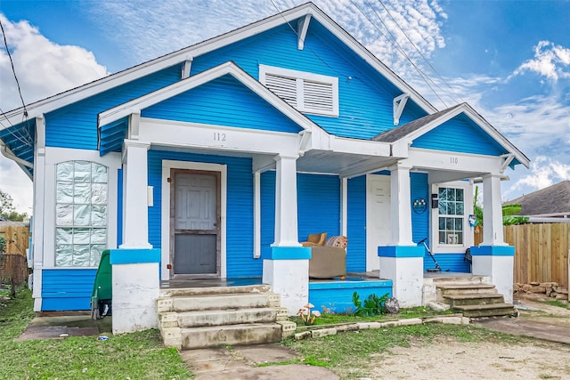 bungalow-style house featuring covered porch and fence