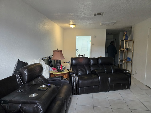 living area with light tile patterned flooring, visible vents, and a textured ceiling