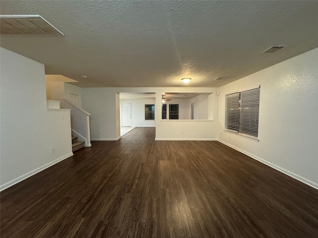 unfurnished living room with visible vents, baseboards, wood finished floors, and stairs