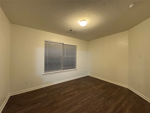 unfurnished room featuring dark wood finished floors, visible vents, a textured ceiling, and baseboards