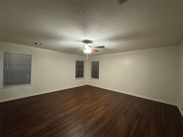 empty room with dark wood-style floors, a textured ceiling, baseboards, and a ceiling fan