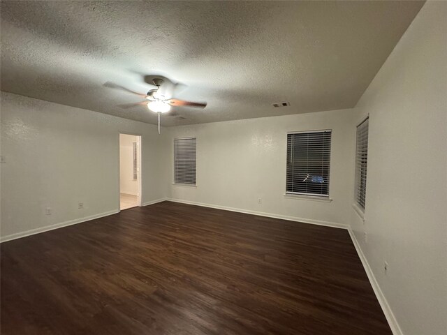 empty room with visible vents, baseboards, a textured ceiling, a ceiling fan, and dark wood-style flooring