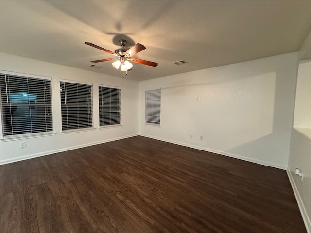 spare room with visible vents, baseboards, dark wood finished floors, and a ceiling fan