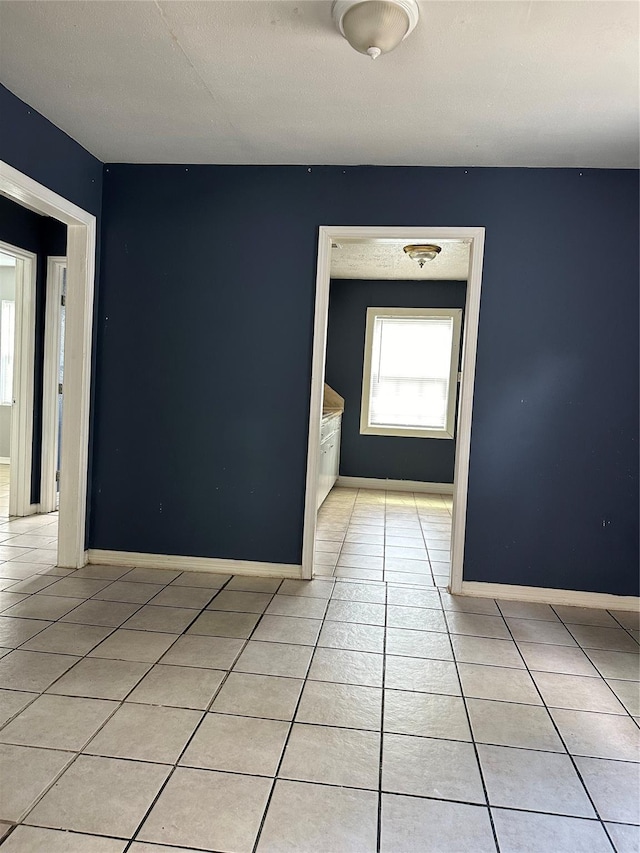 spare room featuring light tile patterned floors and baseboards