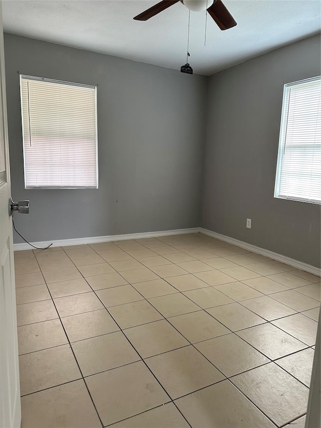 spare room with light tile patterned flooring, baseboards, and a ceiling fan