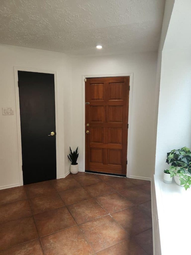 foyer featuring tile patterned flooring, a textured ceiling, and baseboards