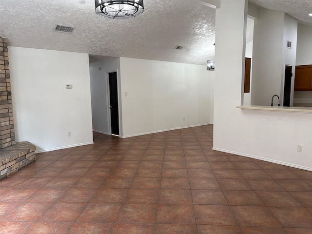 unfurnished living room featuring a sink, visible vents, baseboards, and a textured ceiling