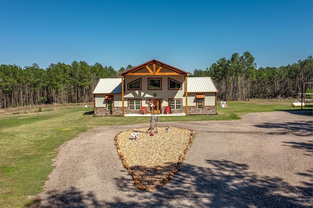 view of front facade featuring metal roof, stone siding, a front yard, and aphalt driveway