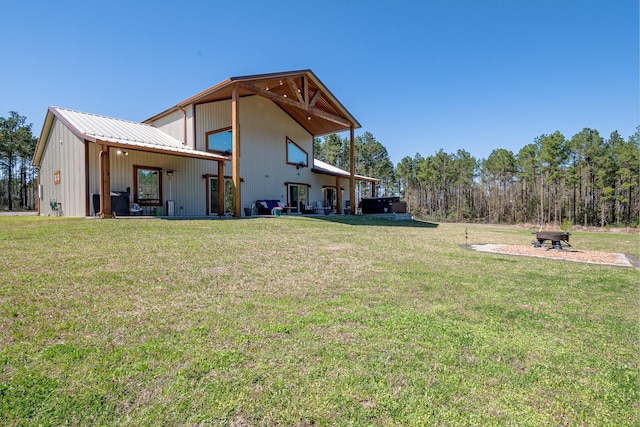 back of property featuring a yard, a fire pit, and metal roof