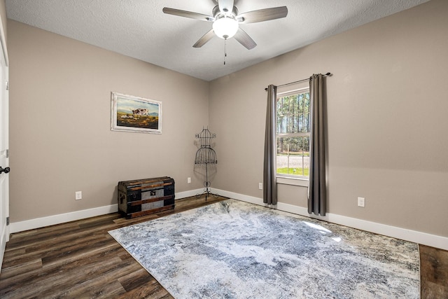 sitting room featuring dark wood finished floors, ceiling fan, a textured ceiling, and baseboards