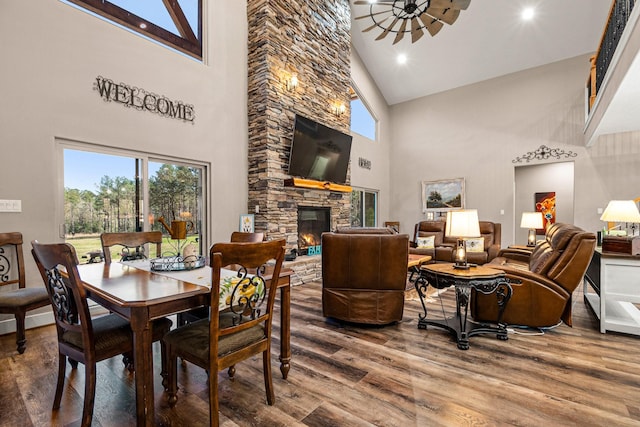 dining area featuring plenty of natural light, a stone fireplace, wood finished floors, and a ceiling fan