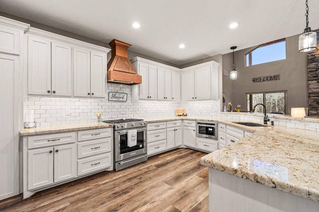 kitchen featuring custom range hood, a sink, wood finished floors, white cabinetry, and gas stove