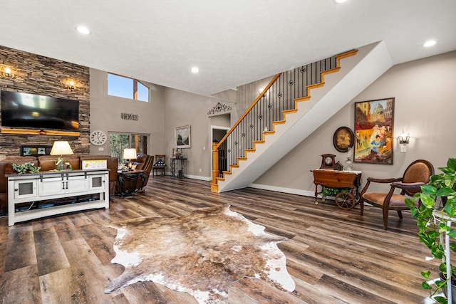 living area with wood finished floors, recessed lighting, stairway, a high ceiling, and baseboards