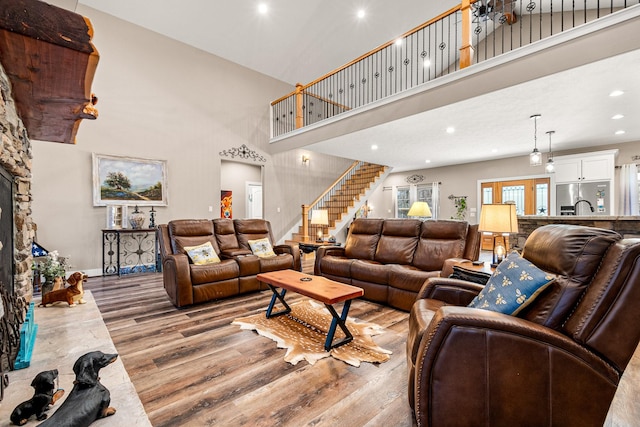 living room featuring wood finished floors, recessed lighting, baseboards, a towering ceiling, and stairs