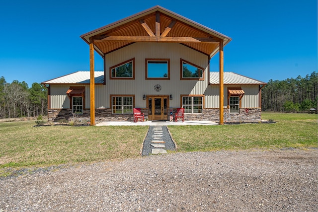 rear view of house with stone siding, french doors, metal roof, and a yard