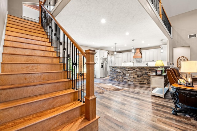 stairs with visible vents, recessed lighting, a textured ceiling, and wood finished floors