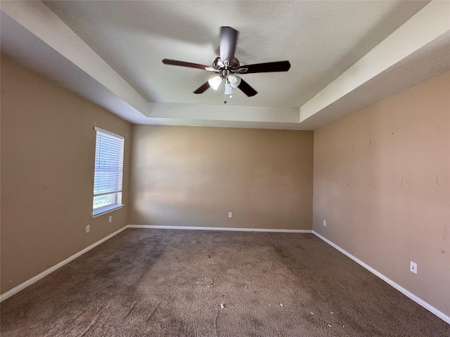 spare room featuring ceiling fan, a raised ceiling, baseboards, and carpet floors