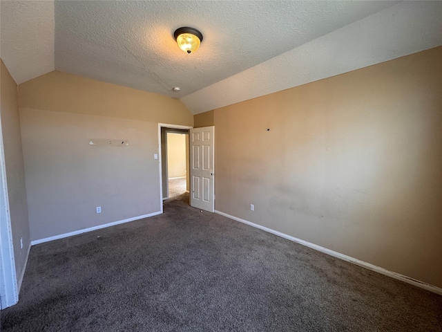 carpeted spare room with vaulted ceiling, baseboards, and a textured ceiling