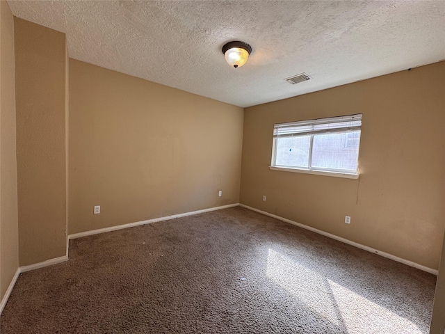 unfurnished room with visible vents, a textured ceiling, and baseboards