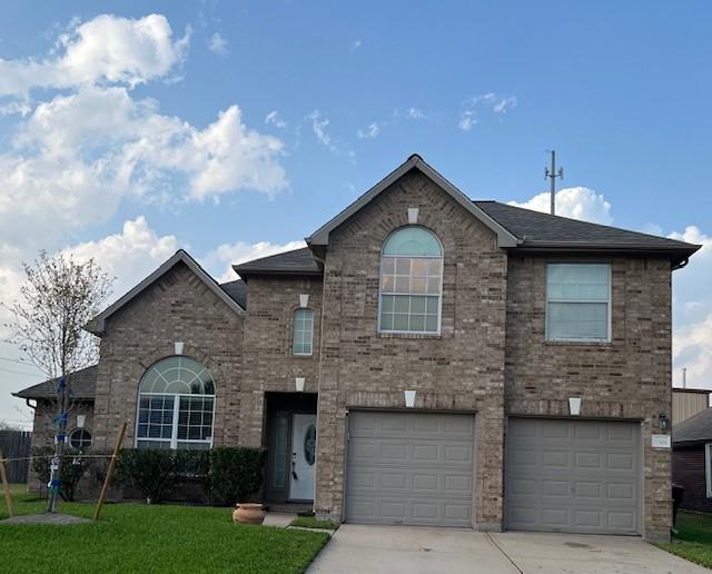 view of front of home featuring a front yard, an attached garage, brick siding, and driveway