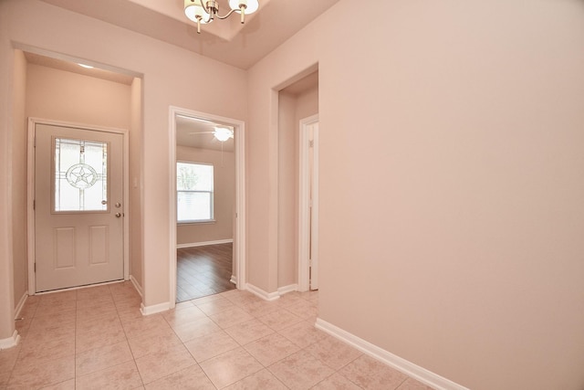 entryway with light tile patterned flooring, baseboards, and an inviting chandelier