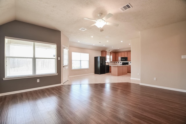 unfurnished living room with visible vents, a textured ceiling, light wood-style flooring, and a ceiling fan