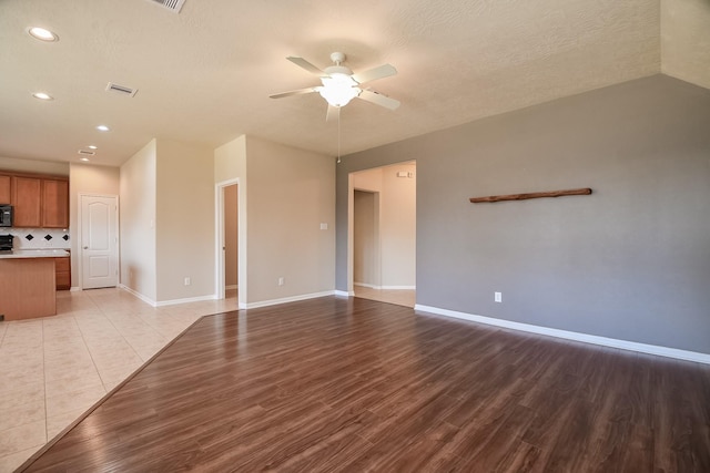 unfurnished living room with light wood finished floors, visible vents, baseboards, and a ceiling fan