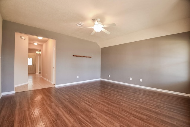 unfurnished room featuring wood finished floors, visible vents, baseboards, ceiling fan, and vaulted ceiling