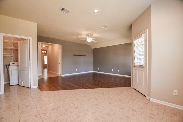 unfurnished room with visible vents, light tile patterned floors, baseboards, washer / dryer, and ceiling fan