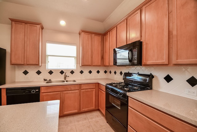 kitchen with light brown cabinetry, light tile patterned floors, decorative backsplash, black appliances, and a sink