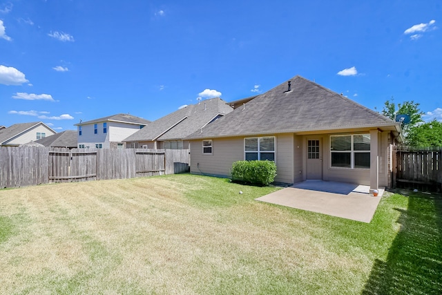 rear view of property featuring a patio, a yard, a fenced backyard, and roof with shingles