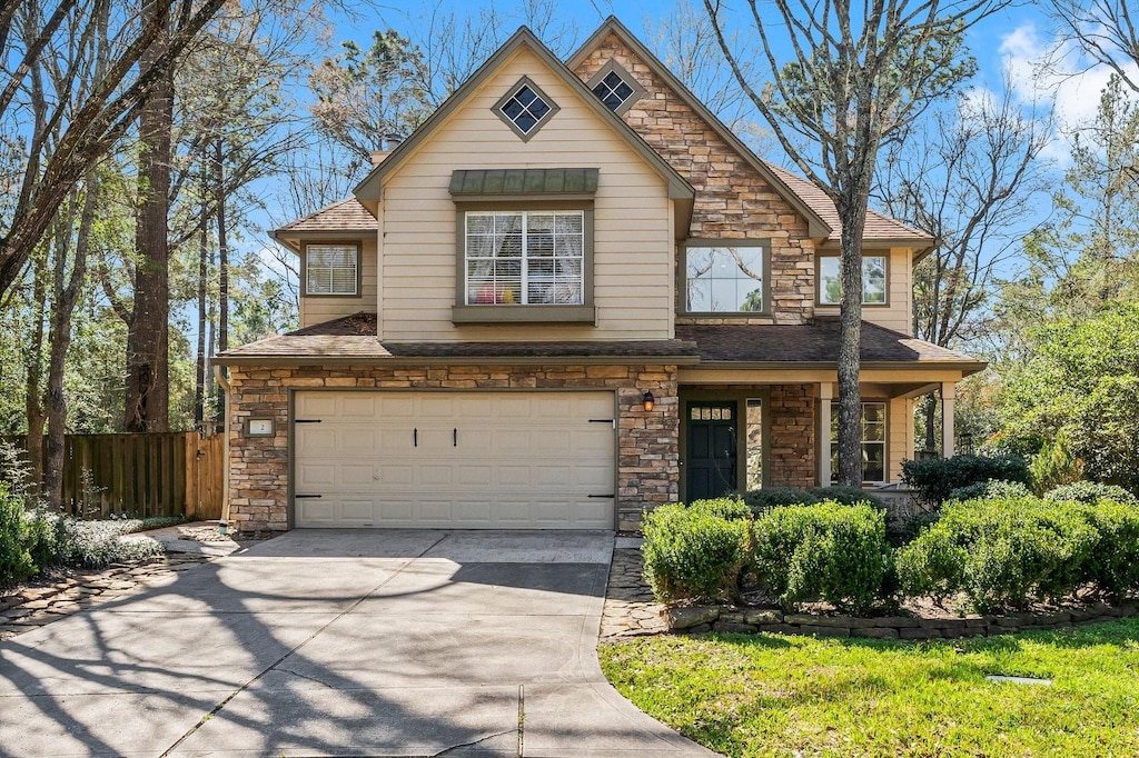 2 S Greywing Pl, The Woodlands, TX 77382 - view of front of home with fence, concrete driveway, roof with shingles, a garage, and stone siding