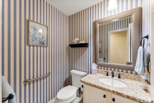 bathroom featuring wallpapered walls, toilet, and vanity