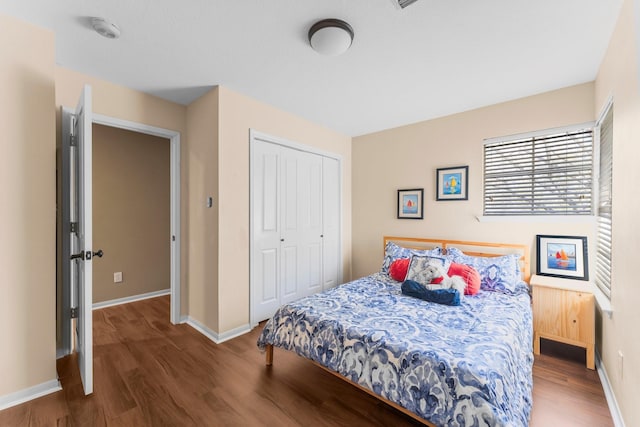 bedroom featuring wood finished floors, baseboards, and a closet