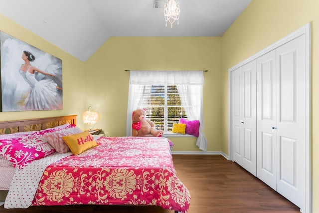 bedroom with vaulted ceiling, wood finished floors, a closet, and baseboards