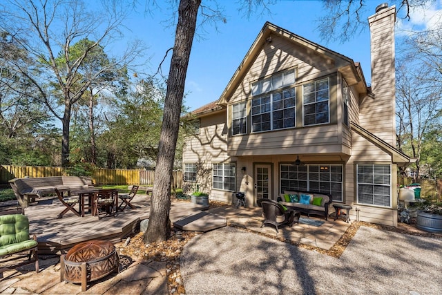 rear view of house with outdoor dining space, a patio, fence, a chimney, and an outdoor living space with a fire pit