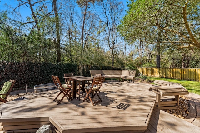 wooden terrace with outdoor dining area and fence