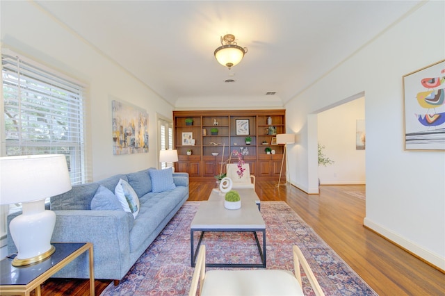 living area with a healthy amount of sunlight, wood finished floors, and visible vents