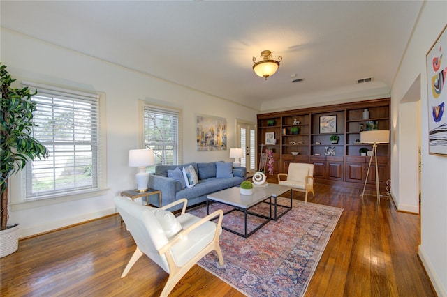 living area with dark wood finished floors, visible vents, and baseboards