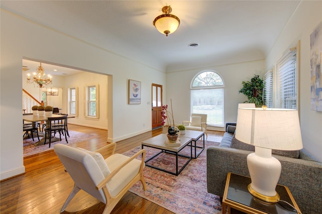 living area with baseboards, an inviting chandelier, and wood finished floors