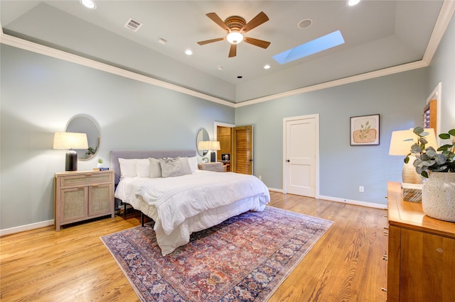 bedroom with visible vents, baseboards, light wood-style floors, a skylight, and a raised ceiling