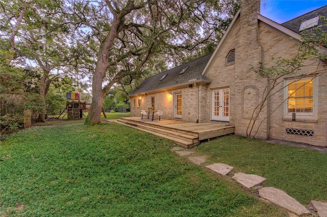 view of yard with a deck, a playground, and french doors