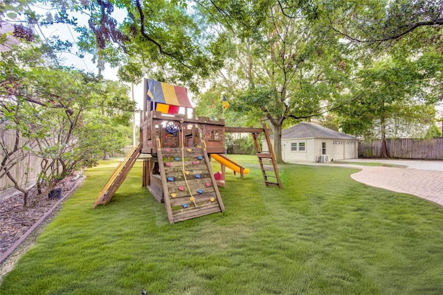 view of playground featuring an outbuilding, a yard, and a fenced backyard