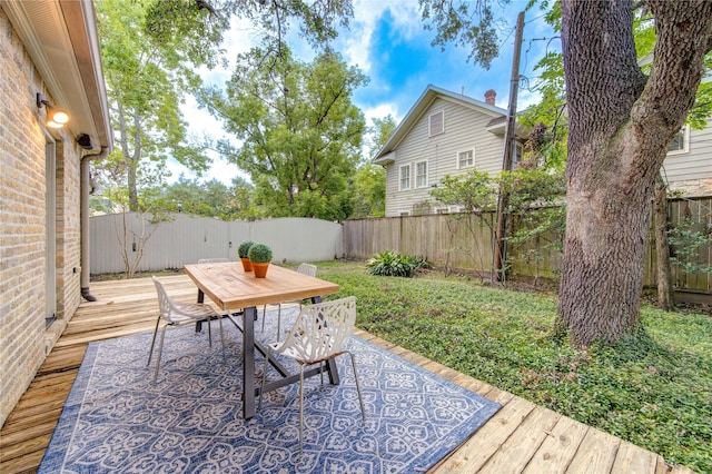 wooden terrace with outdoor dining space and a fenced backyard